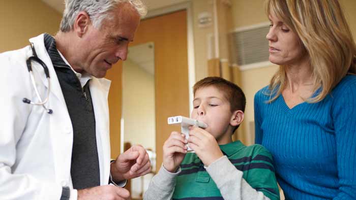 læge, der hjælper et barn med et astmaprodukt