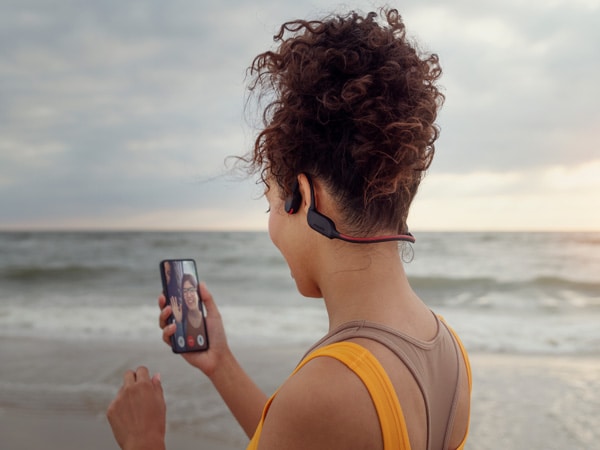 Kvinde, der lytter til et krystalklart opkald i Philips' hovedtelefoner med bone-conduction