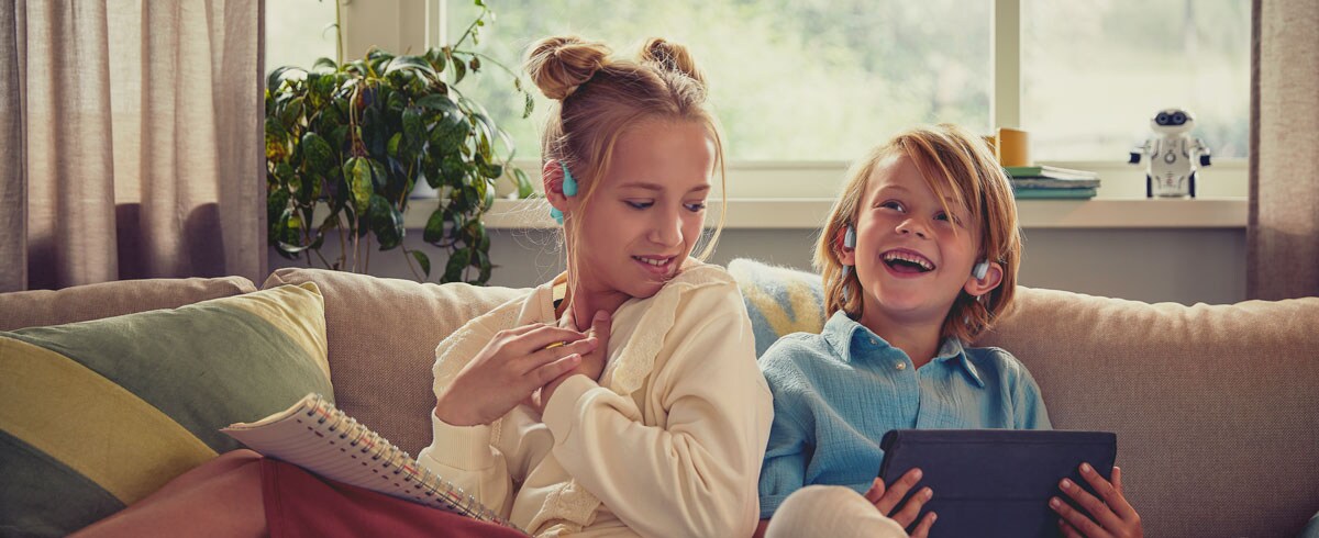 Børn, der ser en video ved hjælp af Philips' open-ear-hovedtelefoner til børn