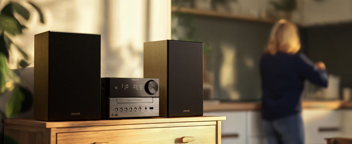 Kvinder lytter til musik i køkkenet fra et Philips-musiksystem