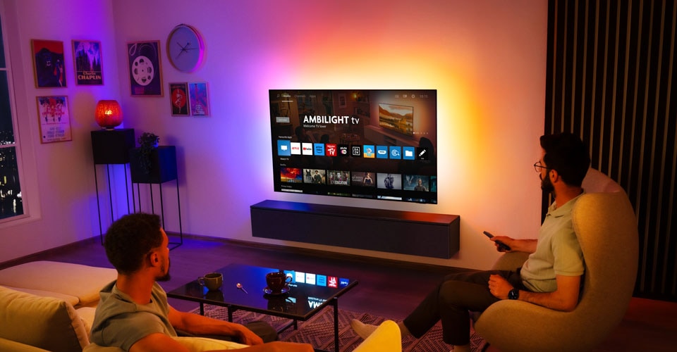 To mænd ser et vægmonteret Ambilight-tv i en stue