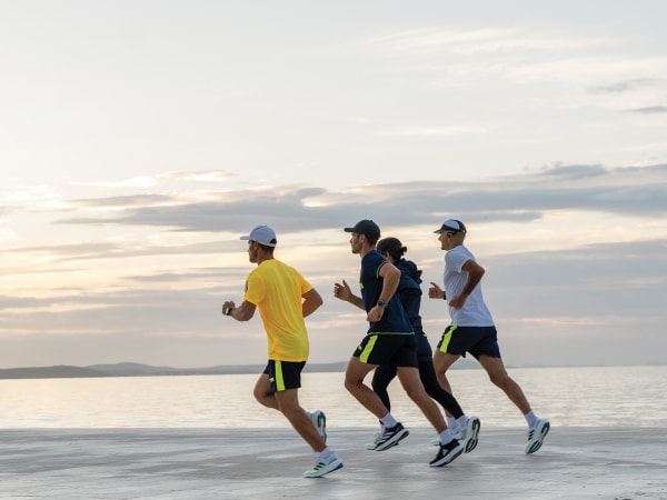 Fire deltagere i løbet løber sammen på stranden.