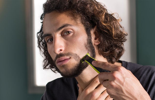 En mand barberer en del af sit skæg i en nedadgående retning, så det bliver til et fipskæg. 