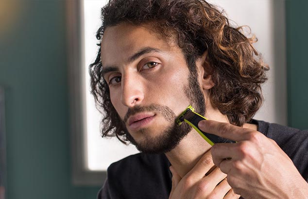En mand er i gang med en tæt barbering af en del af sit stubbede skæg, hvilket resulterer i et formet overskæg.