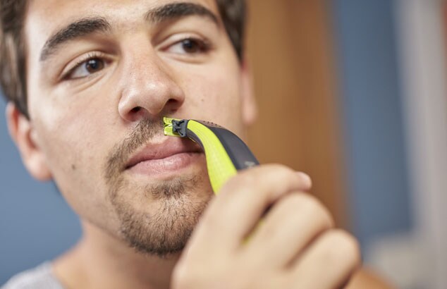 Mand med brunt hår og brune øjne bruger Philips OneBlade til at forme sit goatee over læberne. 