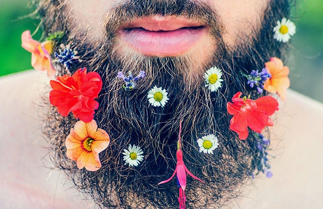 Et nærbillede af en mands skæg, som har en masse forskellige og farverige blomster sat i det. 