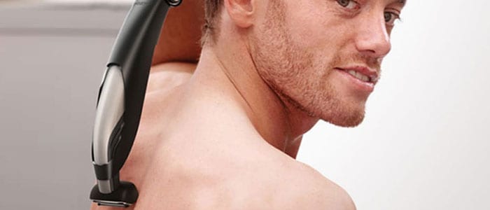 En mand med ryggen til holder en barberingsmaskine og er i gang med at fjerne hård på ryggen og skuldrene.